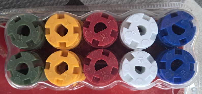 May include: A set of ten multi-colored plastic coupling connectors in a clear plastic package. The connectors are green, yellow, red, white, and blue. Each connector has a central hole and is marked with a number.