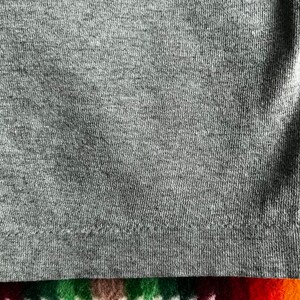 May include: Close-up of a gray knit fabric with a subtle texture. The fabric has a slight sheen and a smooth, soft feel.