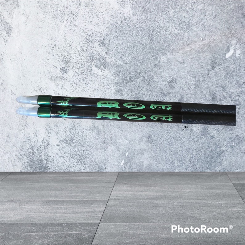 K&ouml;nnte beinhalten: Zwei schwarze Carbonpfeile mit gr&uuml;ner Beschriftung, die auf jedem Pfeil "ROCKET" lautet.