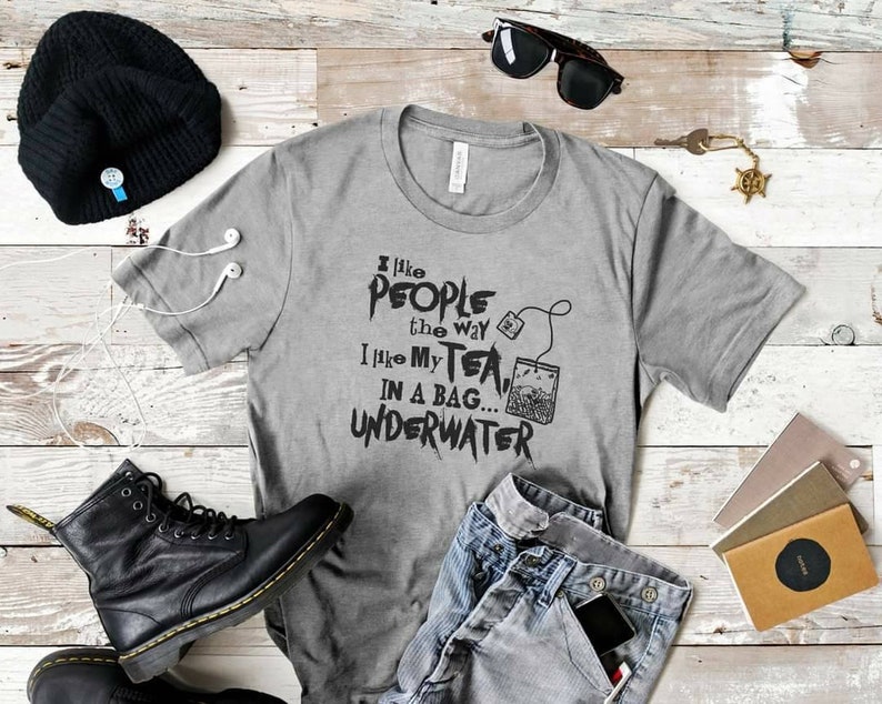 May include: A gray t-shirt with the text "I like people the way I like my tea... in a bag... underwater" printed on it. The text is in black and has a grunge-style font.
