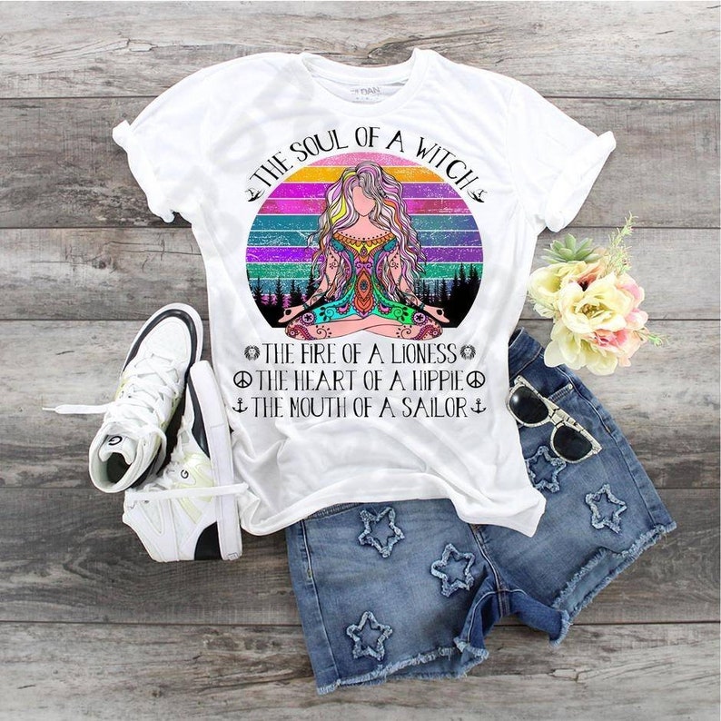 May include: White t-shirt with a colorful retro design of a woman meditating with the text "The Soul of a Witch" and "The fire of a lioness, the heart of a hippie, the mouth of a sailor".