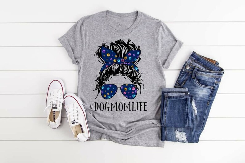 May include: Gray t-shirt with a black and white illustration of a woman with a messy bun, wearing sunglasses and a headband with floral print. The text "#DOGMOMLIFE" is printed below the illustration.