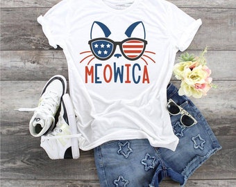 May include: White t-shirt with a cat wearing sunglasses with the American flag design. The text "MEOWICA" is printed below the cat.