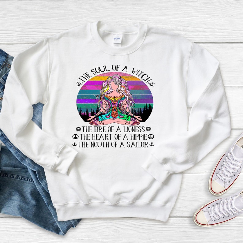May include: White sweatshirt with a colorful graphic of a woman meditating in front of a sunset. The text "The Soul of a Witch" is above the graphic and the text "The Fire of a Lioness, The Heart of a Hippie, The Mouth of a Sailor" is below the graphic.