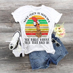 May include: White t-shirt with a vintage-style graphic of a rooster with the text "Your crazy is showing. You might wanna tuck that back in."