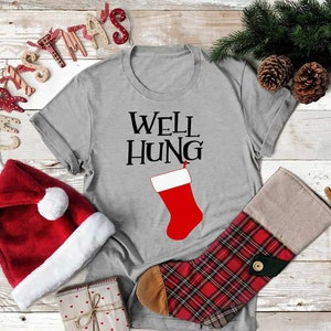 May include: Gray t-shirt with the text "Well Hung" and a red stocking with a white cuff.