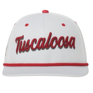 May include: White baseball cap with the word "Tuscaloosa" embroidered in red script. The cap has a red brim and a red button on top. A stylish accessory for fans of Tuscaloosa.