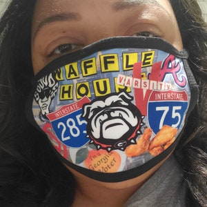 May include: A face mask with a collage of images and text. The mask features the words "WAFFLE HOUSE" in yellow letters, a bulldog, and the text "INTERSTATE 285" and "INTERSTATE 75". The mask also has an image of fried chicken.