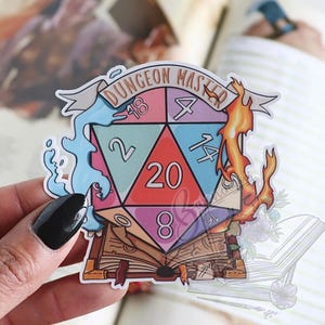 May include: A colourful sticker featuring a D20 die with the text "DUNGEON MASTER" on a banner. The die is surrounded by water and fire elements, and sits atop an open book. The sticker has a white border.