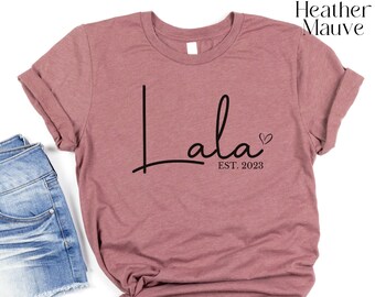 May include: Heather mauve t-shirt with the text "lala" in black script with a small heart and the text "EST. 2023" underneath.
