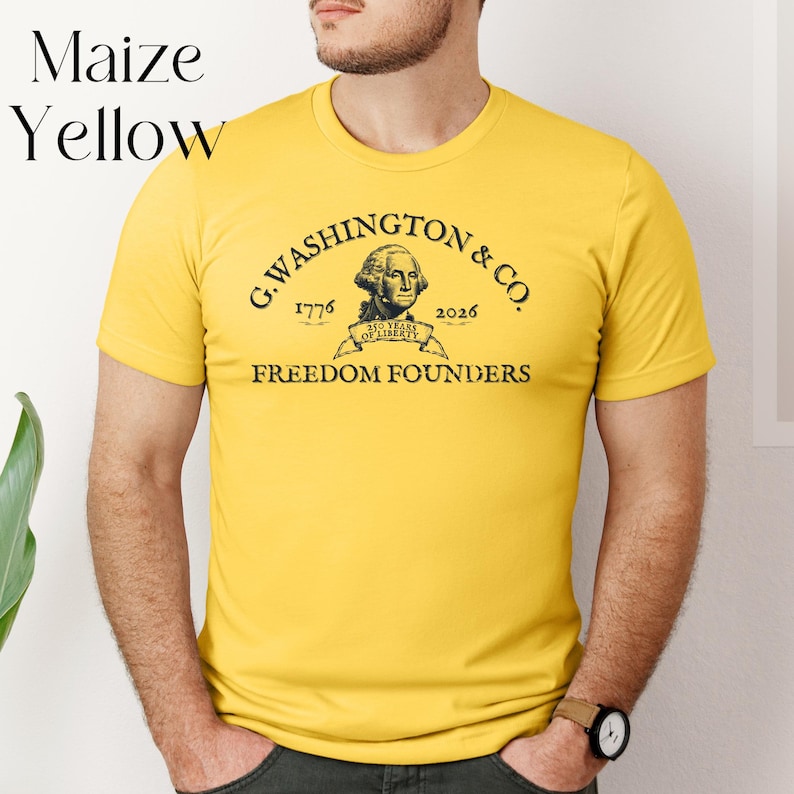 May include: Maize yellow t-shirt with the text "G. Washington & Co. 1776-2026 Freedom Founders" in black. The shirt features a portrait of George Washington. The words "Maize Yellow" are in the upper left corner.