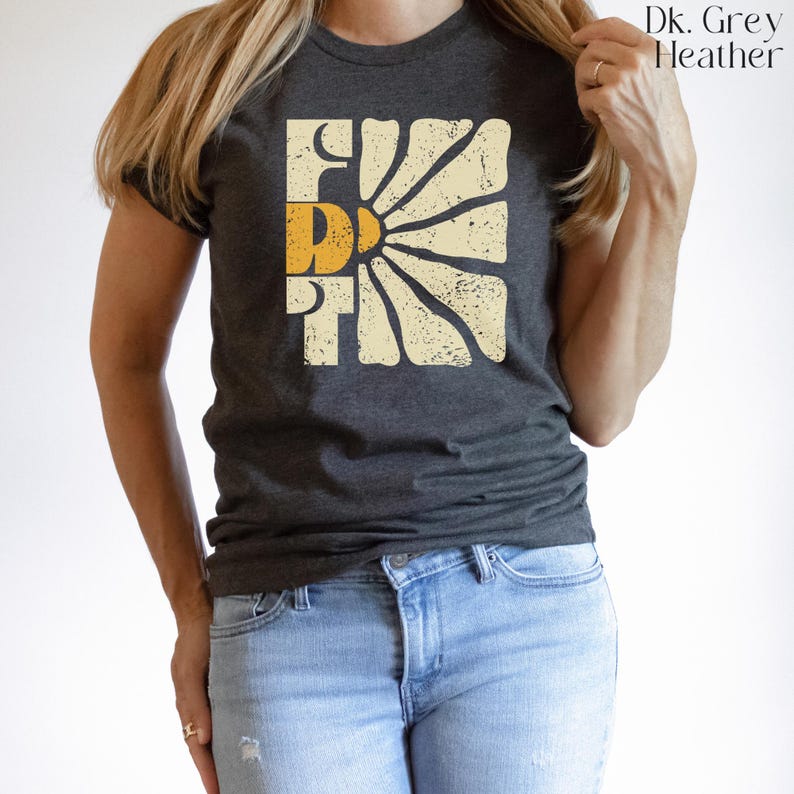 May include: A dark heather grey t-shirt with a vintage-style graphic of a sun with the word "First" in yellow letters.