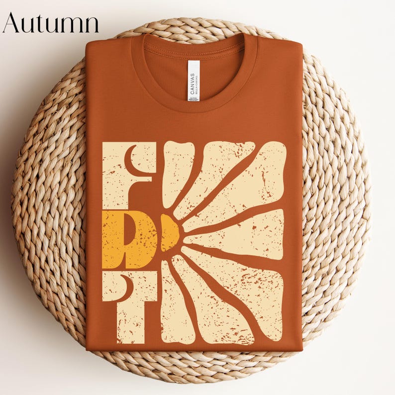 May include: A brown t-shirt featuring a vintage-style graphic of a sun with the word "First" printed in white and yellow.