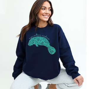 May include: A navy blue sweatshirt with a teal manatee graphic and the text "manatee vibes".