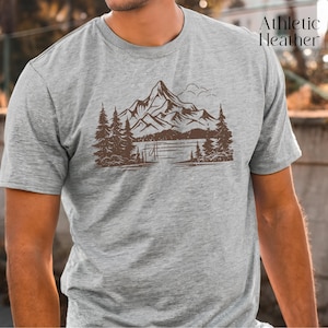 May include: A heather grey t-shirt with a brown mountain scene graphic. The graphic features a mountain range with a lake and trees.