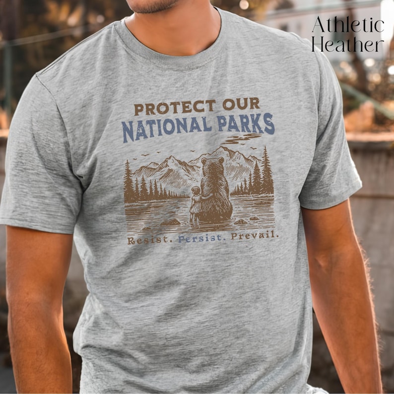 May include: Gray t-shirt with a brown bear and cub illustration. The text "PROTECT OUR NATIONAL PARKS" is printed in blue above the illustration. The text "Resist. Persist. Prevail." is printed in blue below the illustration.
