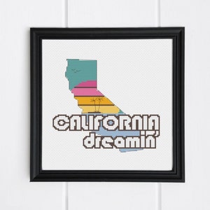 Könnte beinhalten: Ein Kreuzstichmuster mit einer stilisierten Umrandung des Bundesstaates Kalifornien mit Sonnenuntergang und Palmen. Der Text "California dreamin'" befindet sich unterhalb der Umrandung.