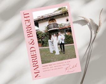 May include: A pink wedding announcement card with a photo of a bride and groom walking in a garden. The text "Married & Bright" is in red on the left side of the card. The text "Thank you for sharing in our special day, wishing you the happiest of holidays!" is in red on the bottom of the card. The couple's names are written in cursive in red on the bottom right corner of the card.