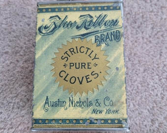 May include: Vintage Blue Ribbon Brand spice tin for cloves. The rectangular tin has a gold and blue design with the words "Strictly Pure Cloves" and "Austin Nichols & Co. New York." A yellow measuring tape is next to the tin.