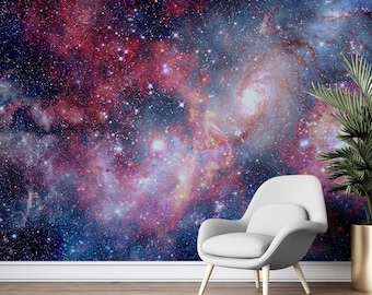 May include: A vibrant galaxy-themed wall mural with swirling nebulae in shades of red, purple, and blue. A white modern chair and a potted plant with green leaves are in front of the mural. The room has a wooden floor.