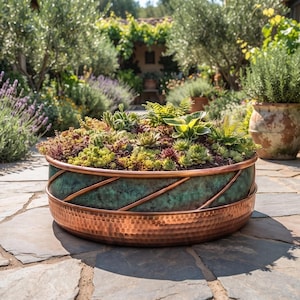 May include: A round, low-profile planter featuring a hammered copper base and a teal-patina upper section with diagonal copper bands. The planter is filled with a variety of small, dense succulents in shades of green, yellow, and deep purple.