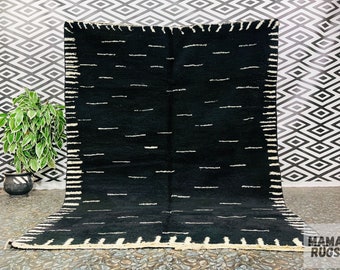 May include: Black and white striped rug with a white border. The rug has a simple geometric design and is made of wool.