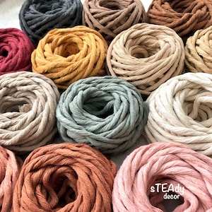 May include: Assortment of colorful cotton rope in various shades, including red, orange, yellow, green, brown, beige, and pink. The rope is arranged in a circle, with the ends of each rope overlapping. The rope is thick and textured, and the colors are vibrant and rich.