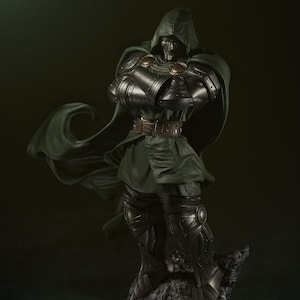 May include: A detailed, green and silver statue of Doctor Doom, a Marvel Comics supervillain, standing on a rocky base. He is wearing a green cape and a metal mask.