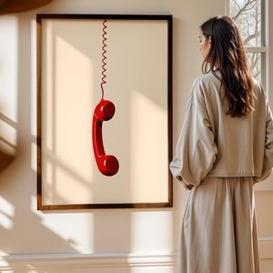 May include: A framed print of a red telephone receiver hanging from a coiled cord against a light beige background.