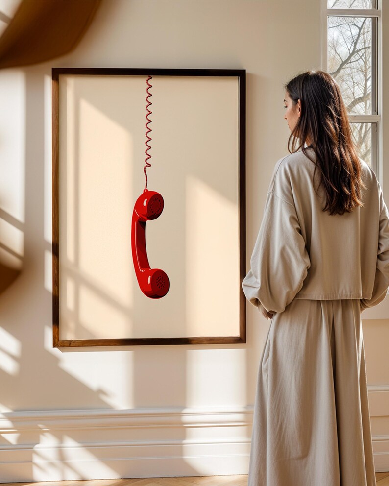 May include: A framed print of a red telephone receiver hanging from a coiled cord against a light beige background.