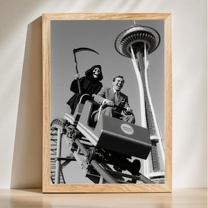 Könnte beinhalten: Gerahmter Schwarz-Weiß-Druck, der einen Mann und den Sensenmann auf einer Achterbahn zeigt, mit der Space Needle im Hintergrund. Der Achterbahnwagen hat ein rundes Logo. Das Bild ist in einem Holzrahmen.