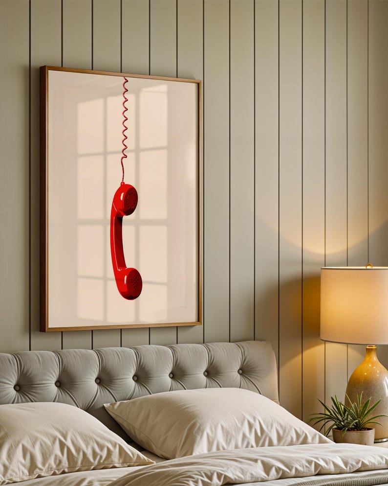 May include: A framed print of a red rotary phone receiver hanging from a coiled cord against a white background.