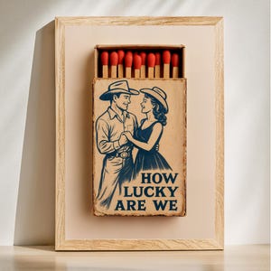 Peut inclure: Une illustration vintage de boîte d'allumettes représentant un couple en chapeaux de cow-boy dansant avec le texte "HOW LUCKY ARE WE" imprimé en dessous.