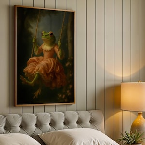 May include: A framed art print depicts a green frog in a pink dress on a swing. The frog has red eyes and is set against a dark forest background. The artwork is displayed above a bed with a tufted headboard.