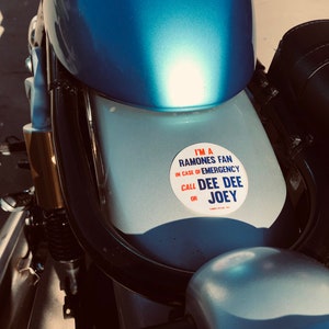 May include: A blue motorcycle with a white sticker that says "I'm a Ramones fan. In case of emergency call Dee Dee or Joey."