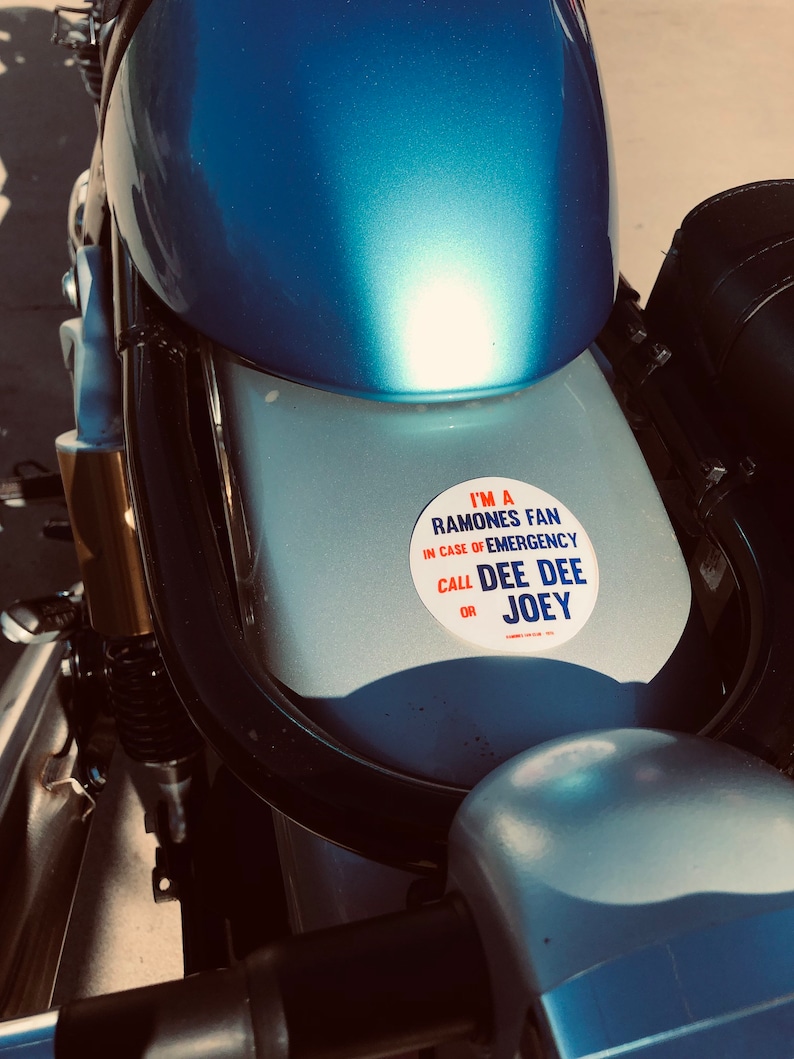 May include: A blue motorcycle with a white sticker that says "I'm a Ramones fan. In case of emergency call Dee Dee or Joey."
