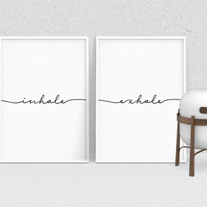 May include: Two white framed prints with black calligraphy. The left print says "inhale" and the right print says "exhale".