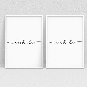 May include: Two white framed prints with black calligraphy. The left print says "inhale" and the right print says "exhale".