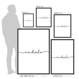 May include: A comparison of different sizes of framed prints with the word "inhale" in a cursive font. The prints are shown next to a person for scale. The sizes are 11x14 inches, 16x20 inches, 18x24 inches, 33.1x44.9 inches, and 24x36 inches.
