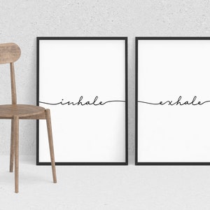 May include: Two black framed prints with white backgrounds and black cursive text. The left print says "inhale" and the right print says "exhale".