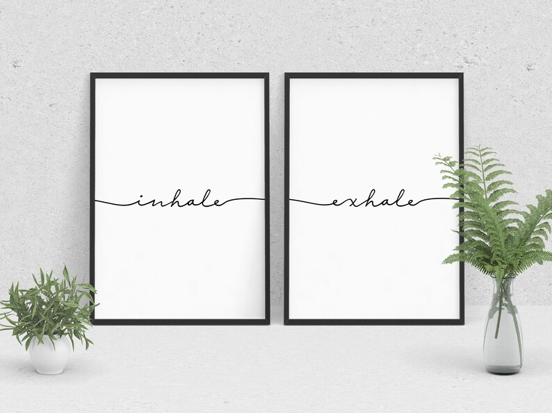May include: Two black framed prints with white backgrounds. The left print has the word "inhale" written in black cursive. The right print has the word "exhale" written in black cursive.