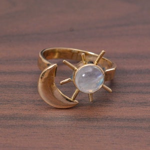 Peut inclure: Bague en or avec un motif de croissant de lune et un soleil avec une pierre de lune ronde au centre.