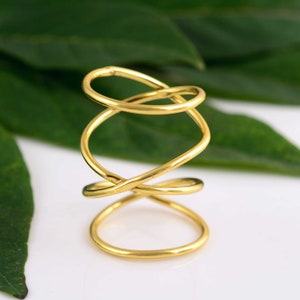 May include: Gold-toned ear cuff with a twisted, spiral design. The cuff is made of multiple intertwined rings.