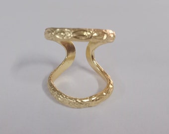 May include: A gold-colored ring with a decorative design. The ring is open on one side and has a curved shape.