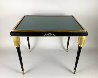 May include: A black and gold side table with a green glass top. The table has four legs with gold accents.
