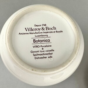 May include: Close-up of the bottom of a white ceramic bowl with brown text that reads "Depuis 1748 Villeroy & Boch Ancienne Manufacture Imp&eacute;riale et Royale Luxembourg Botanica VITRO-Porcelaine * Garanti lave-vaisselle Sp&uuml;lmaschinenfest Dishwasher safe".