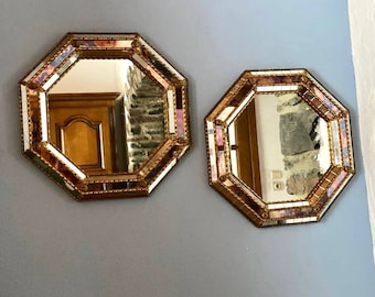 Könnte beinhalten: Zwei achteckige goldene Spiegel mit abgeschrägten Kanten und einem Mosaik aus kleinen Spiegelkacheln. Die Spiegel hängen an einer hellblauen Wand.