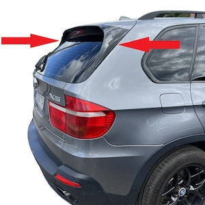 以下が含まれることがあります： 黒いリアスポイラーと黒いホイールを備えたグレーのBMW X5 SUV。リアウィンドウはスモークがかかっており、車は黒いバンパーを備えています。