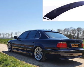 Könnte beinhalten: Ein schwarzer BMW 7er Limousine mit einem Heckspoiler. Das Auto steht auf einem Feldweg mit grünem Gras auf beiden Seiten. Das Kennzeichen lautet "34-GV-HH".
