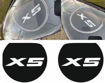 May include: Two black round stickers with white text that reads "X5" in a stylized font.